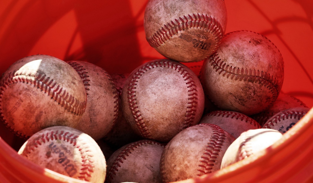 Красное ведро с мячами для бейсбола