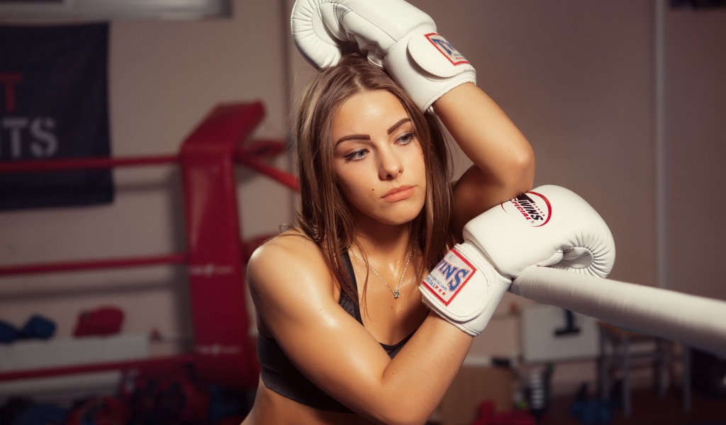 Девушка в белых перчатках отдыхает у канатов ринга