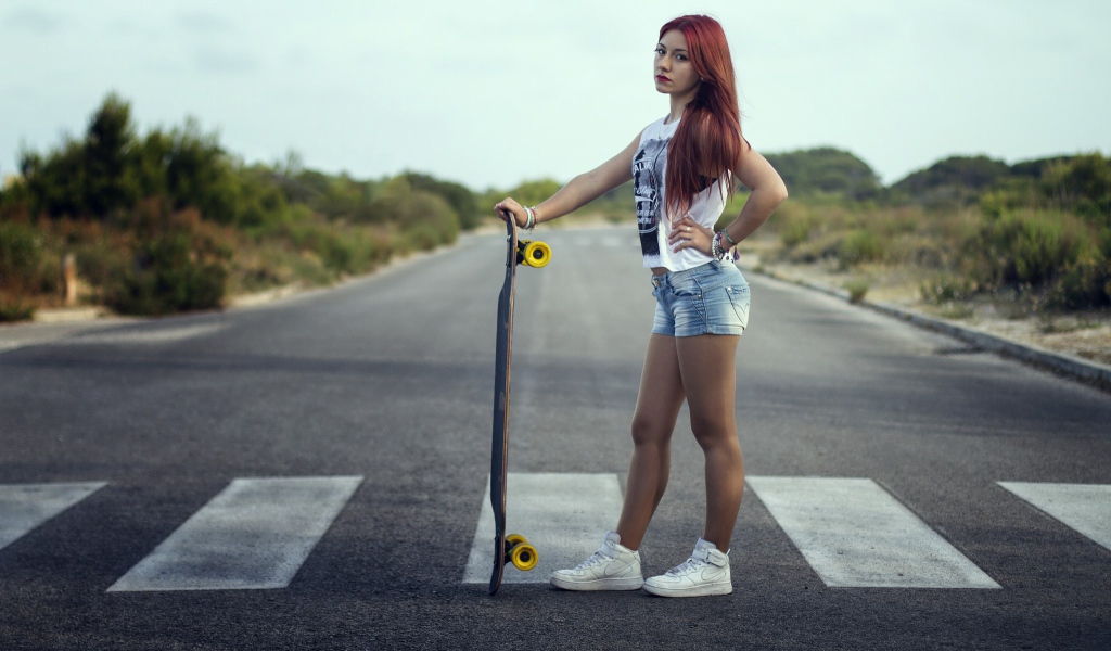 Девушка со скейтбордом стоит на переходе