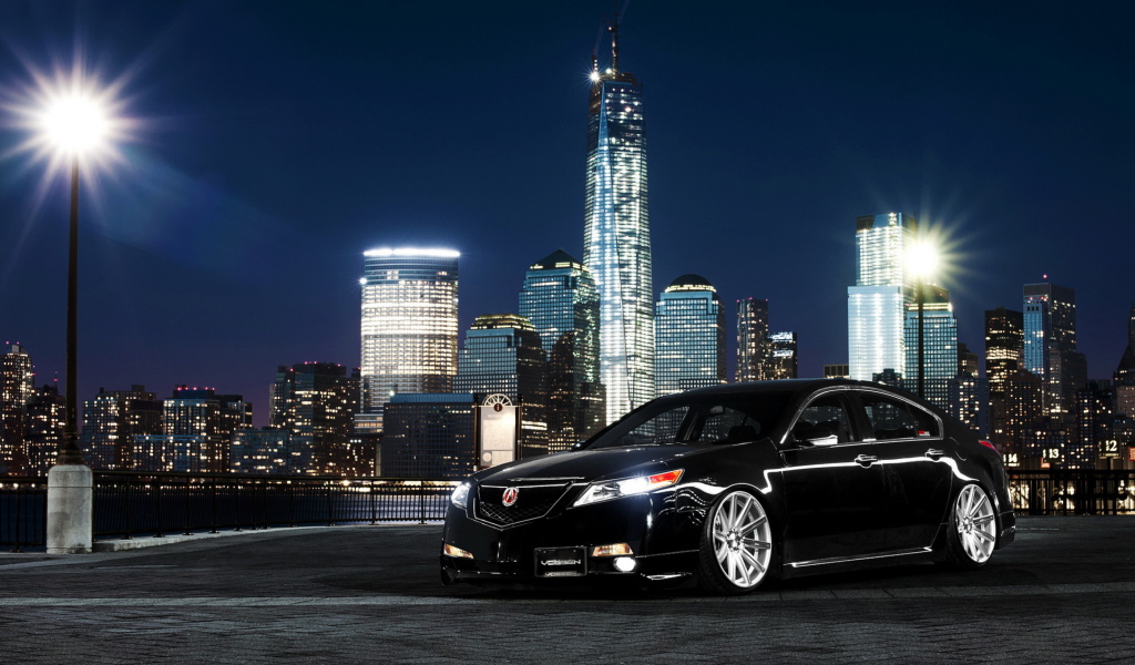 Черный автомобиль Acura TL на фоне ночных небоскребов 