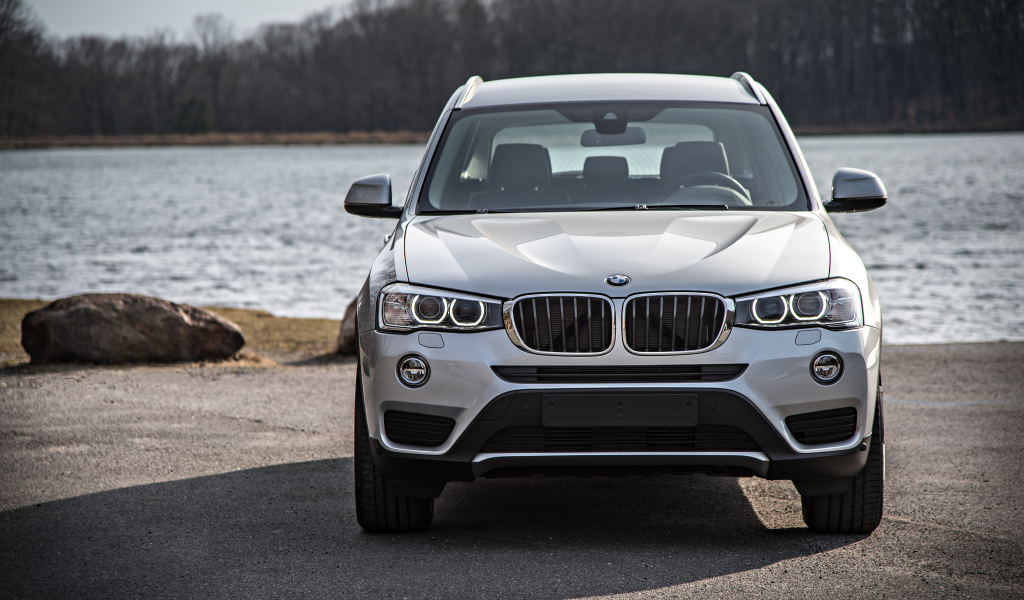 Серебристый автомобиль BMW X3 у водоема 