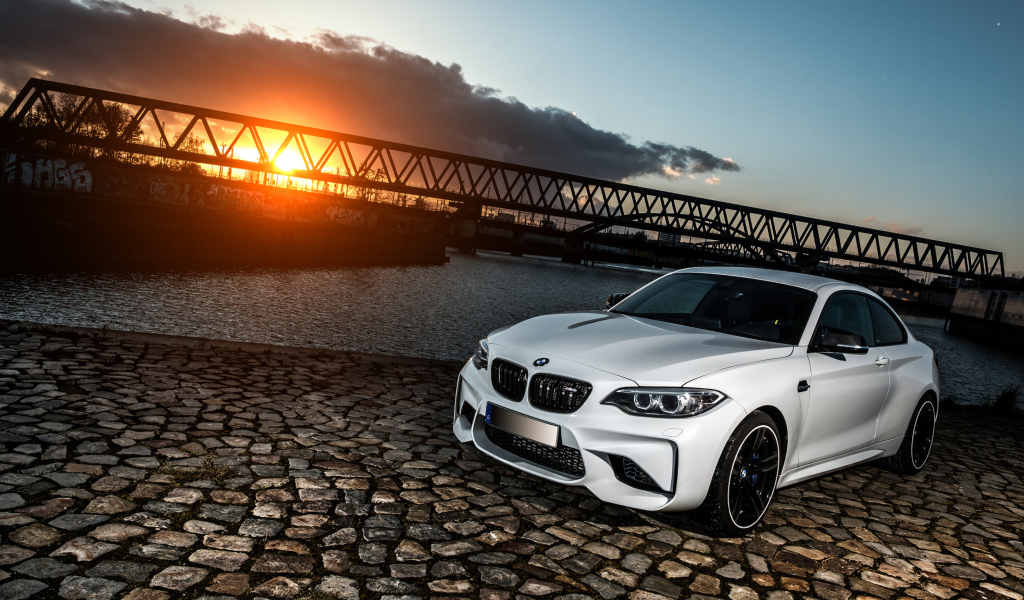 Белый автомобиль BMW M2 на фоне заката 