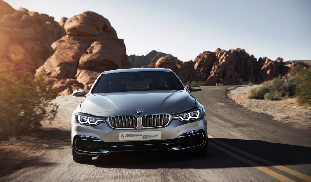 Серебристый автомобиль BMW 4 Series Coupe на дороге у скал