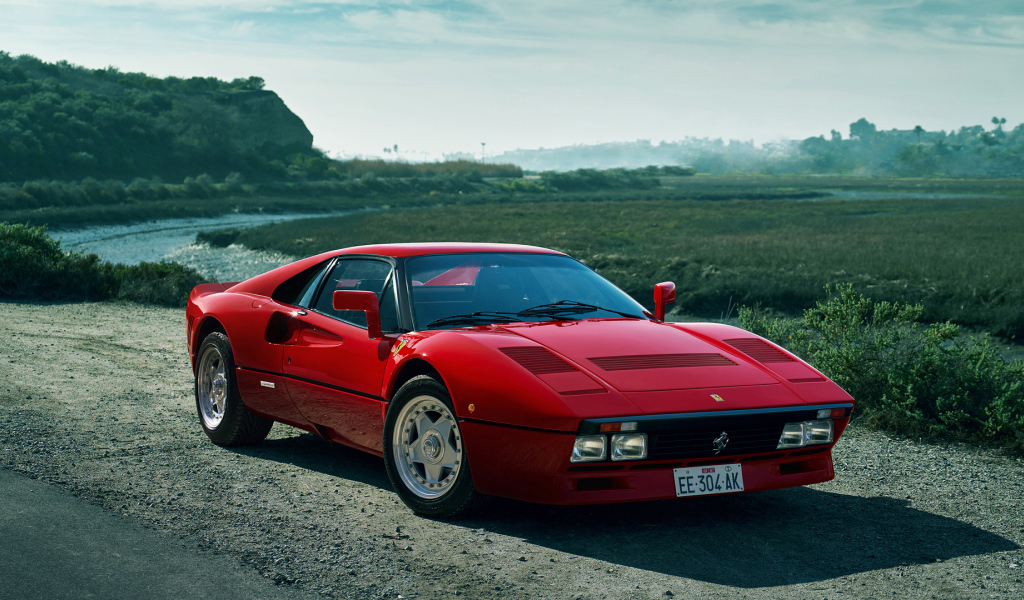 Красный быстрый автомобиль Ferrari 288 GTO у реки