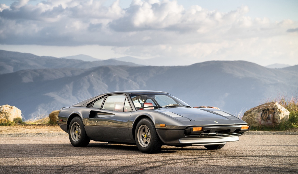 Суперкар Ferrari 308 gts серого цвета,   на фоне гор 