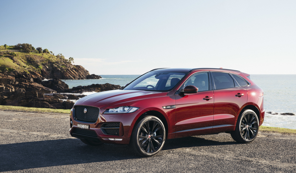 Бордовый автомобиль Jaguar F-Pace на фоне океана