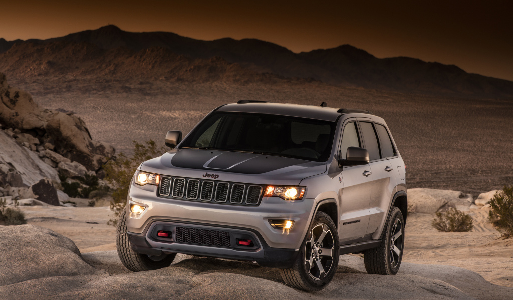 Серебристый внедорожник Jeep Grand Cherokee в пустыне 