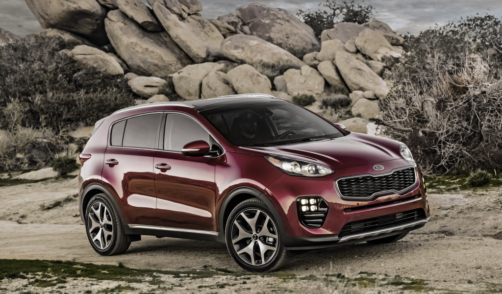 Стильный бордовый внедорожник Kia Sportage на фоне больших камней