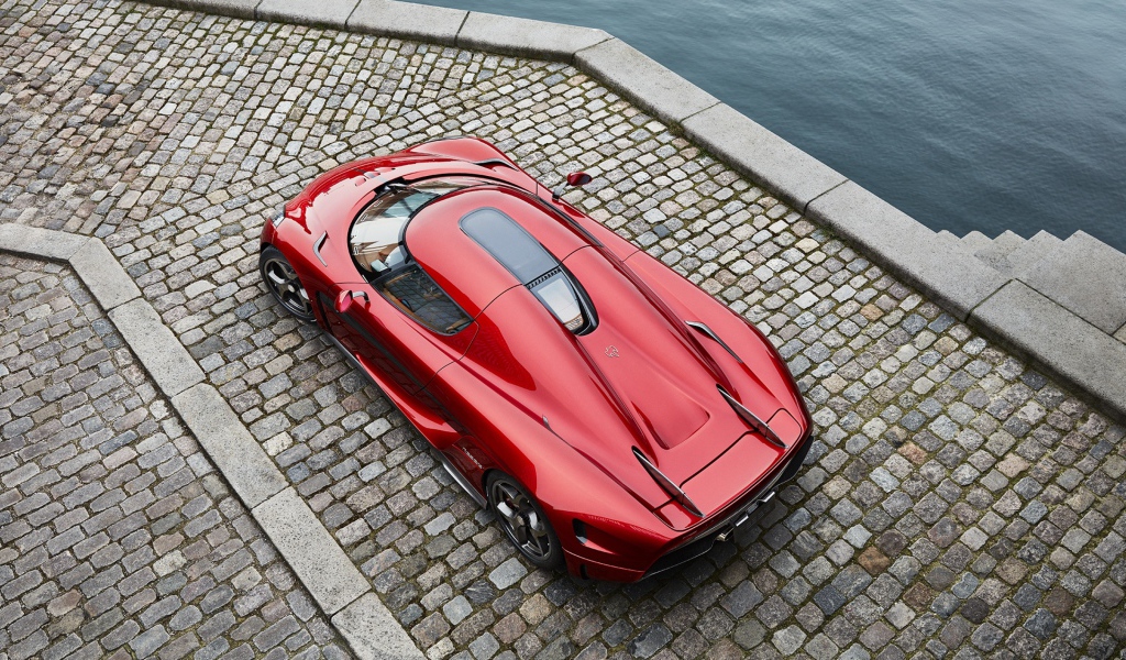 Красный спортивный автомобиль Koenigsegg Regera у воды, вид сверху