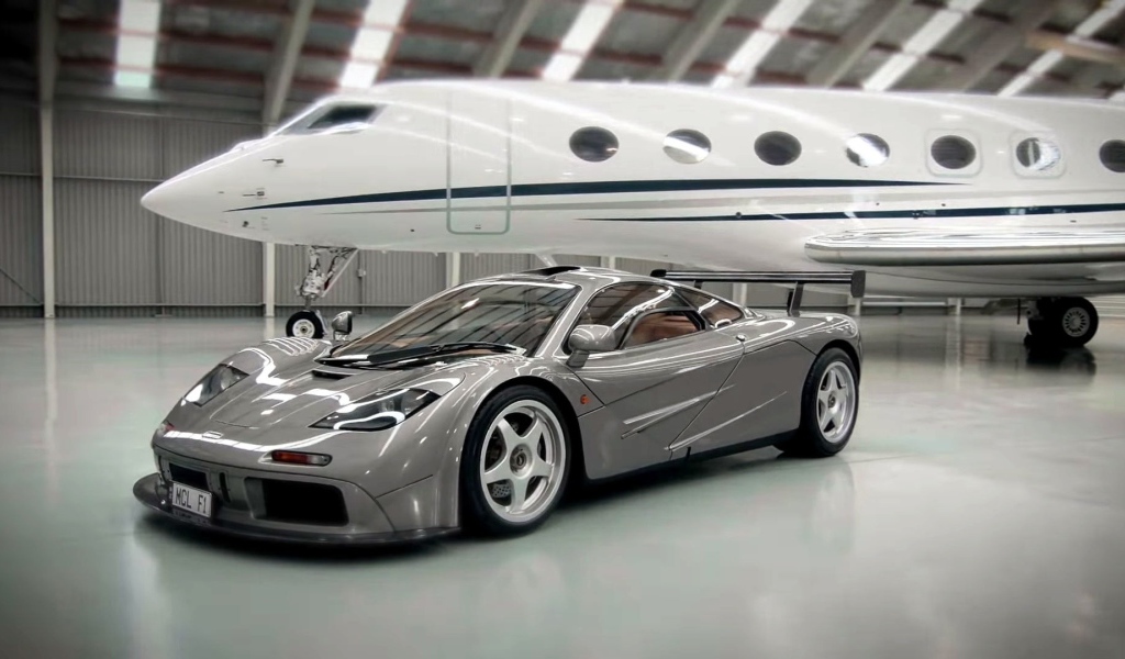 Спортивный автомобиль McLaren F1 на фоне самолета