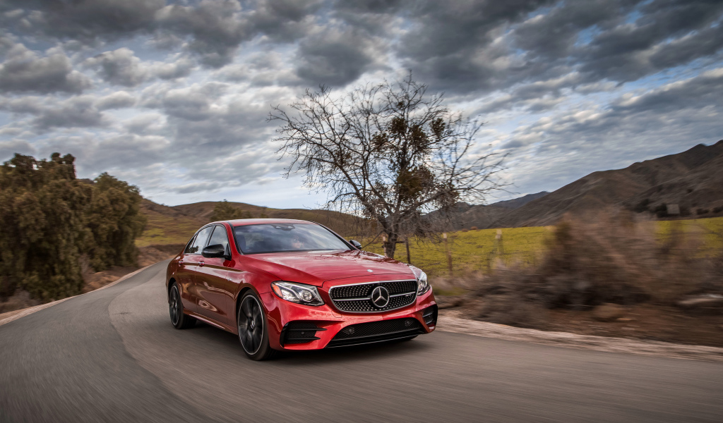 Стильный красный автомобиль Mercedes-Benz E-Class на фоне неба 