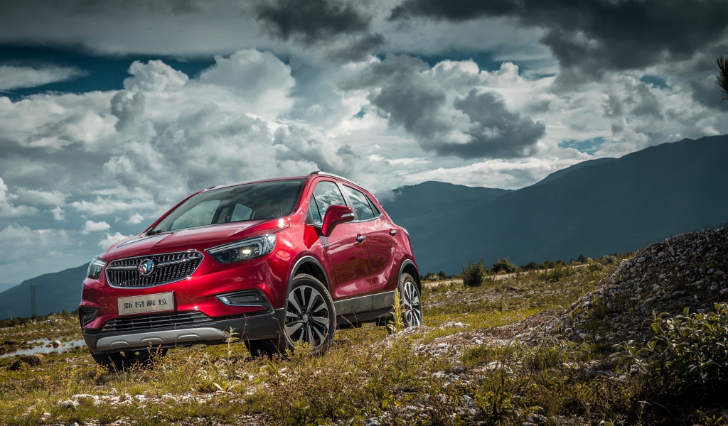 Красный автомобиль Opel Mokka на фоне облачного неба 