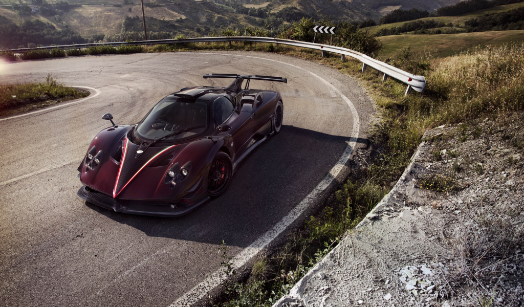 Быстрый бордовый автомобиль Pagani Zonda на крутом повороте
