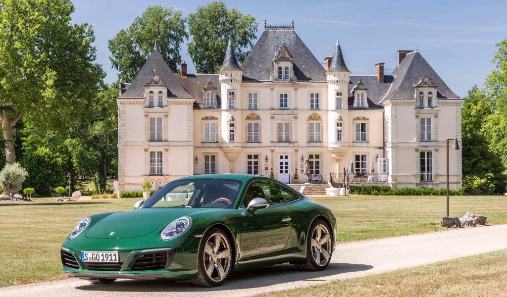 Зеленый спортивный автомобиль Porsche 911 Carrera на фоне дома