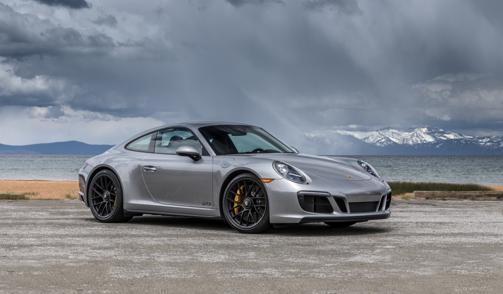 Silver car Porsche 911 Carrera 4 GTS Coupe in the background of a stormy sky