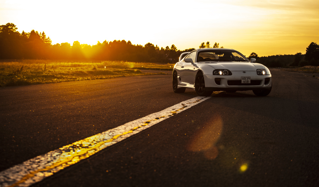 Белый автомобиль Toyota Supra стоит на трассе на рассвете