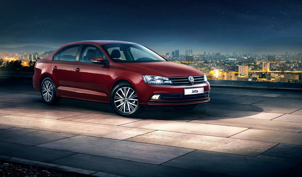 Красный автомобиль Volkswagen Jetta на фоне ночного города