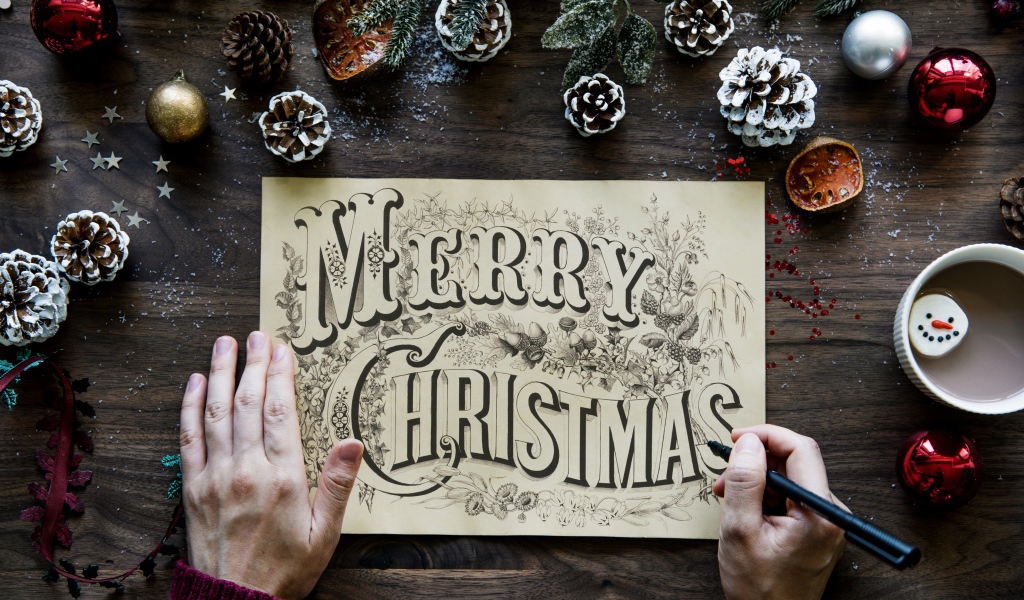 Рисунок с надписью Merry Christmas на столе с новогодними украшениями