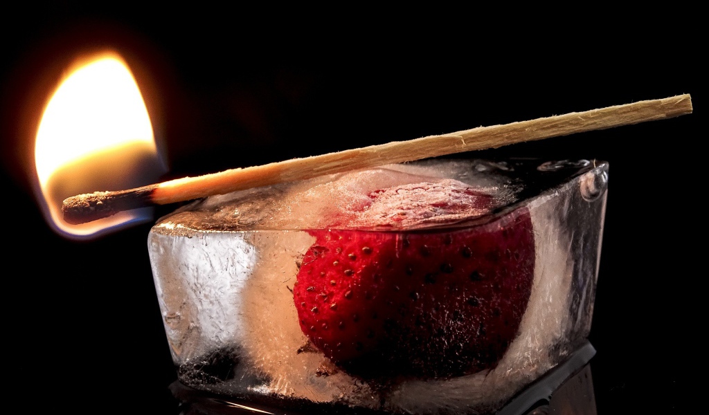 Зажженная спичка на кусочке льда с клубникой 
