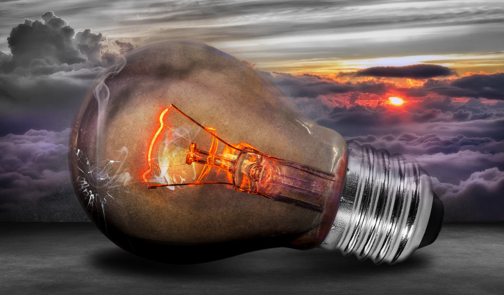 Раскаленная лампочка на фоне белых облаков в небе