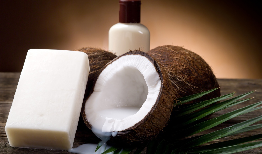 Кокосовое масло с кокосовым мылом и свежими кокосовыми орехами на зеленых листьях