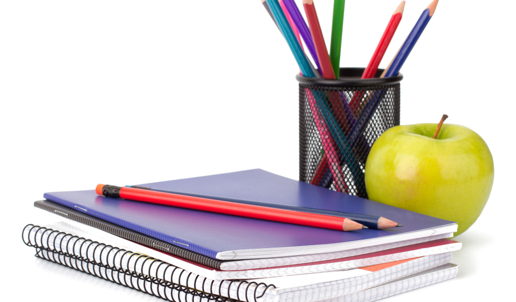 Тетради, карандаши и зеленое яблоко на белом фоне