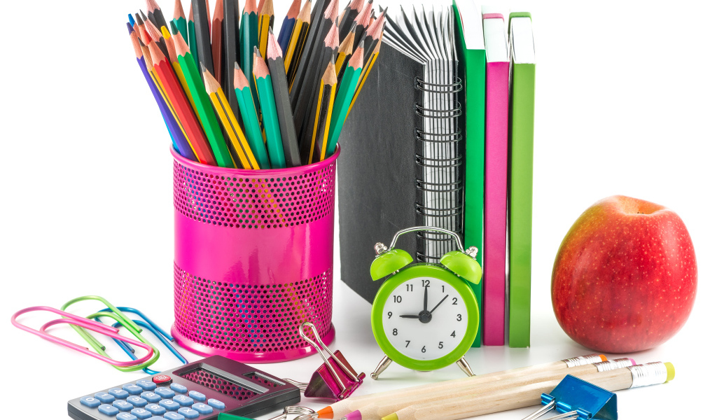 Канцелярские товары и красное яблоко на белом фоне