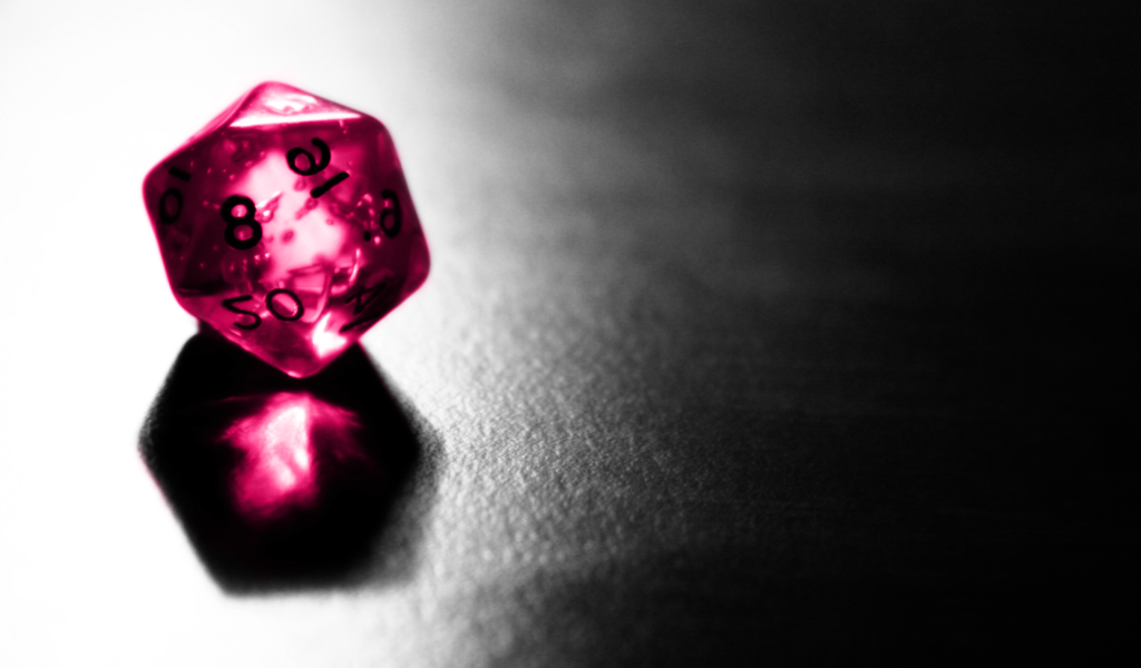 Розовый фигурный кубик отражается серой поверхности стола