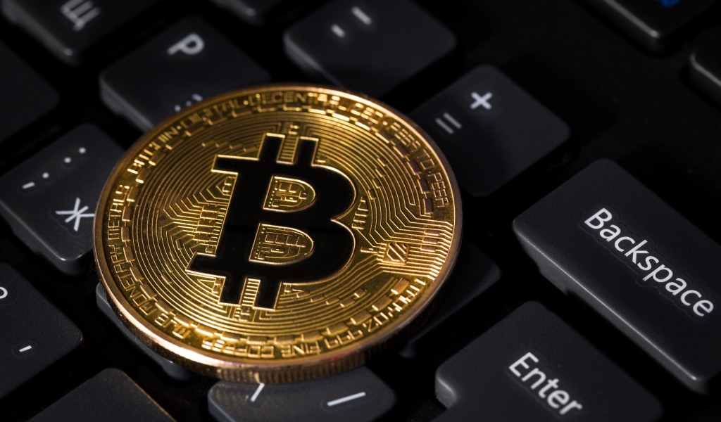 Монета биткоин лежит на черной клавиатуре