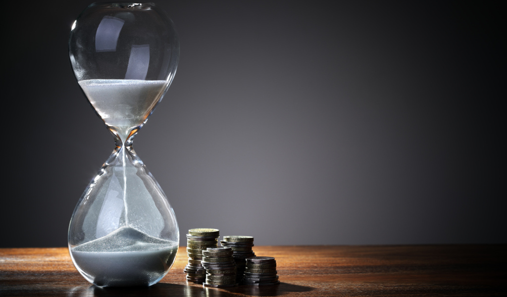 Монеты и песочные часы на столе