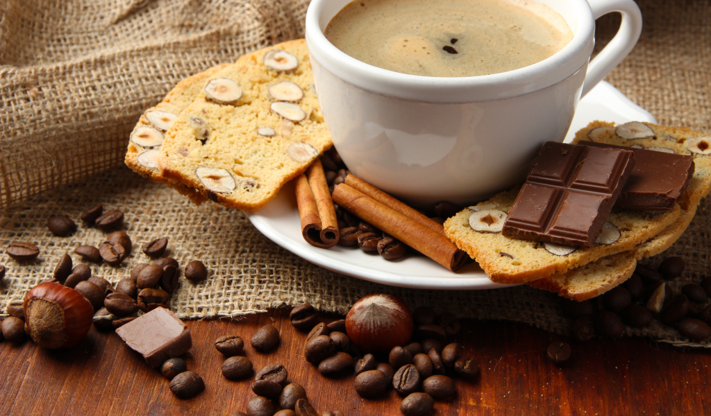 Чашка кофе с выпечкой, кофейными зернами и шоколадом