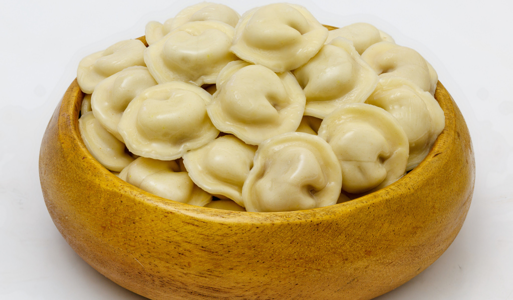 Аппетитные пельмени в деревянной миске на сером фоне