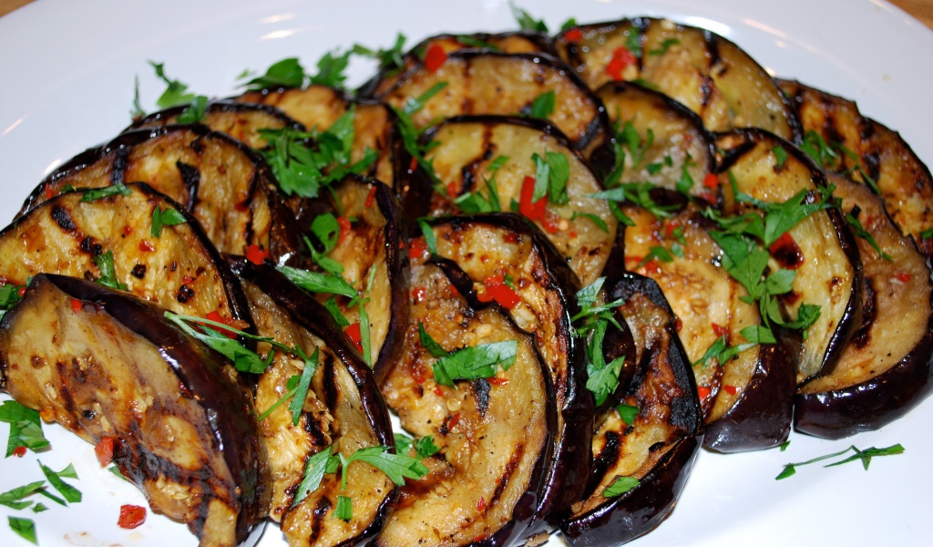 Аппетитные жареные баклажаны на тарелке с зеленью