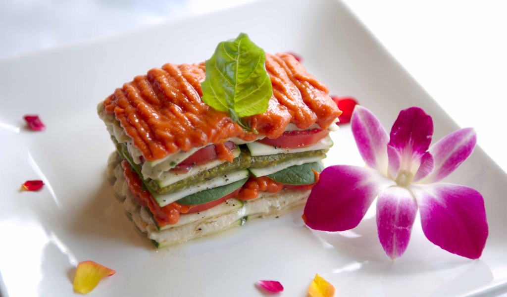 Аппетитный овощной бутерброд на белой тарелке с цветком