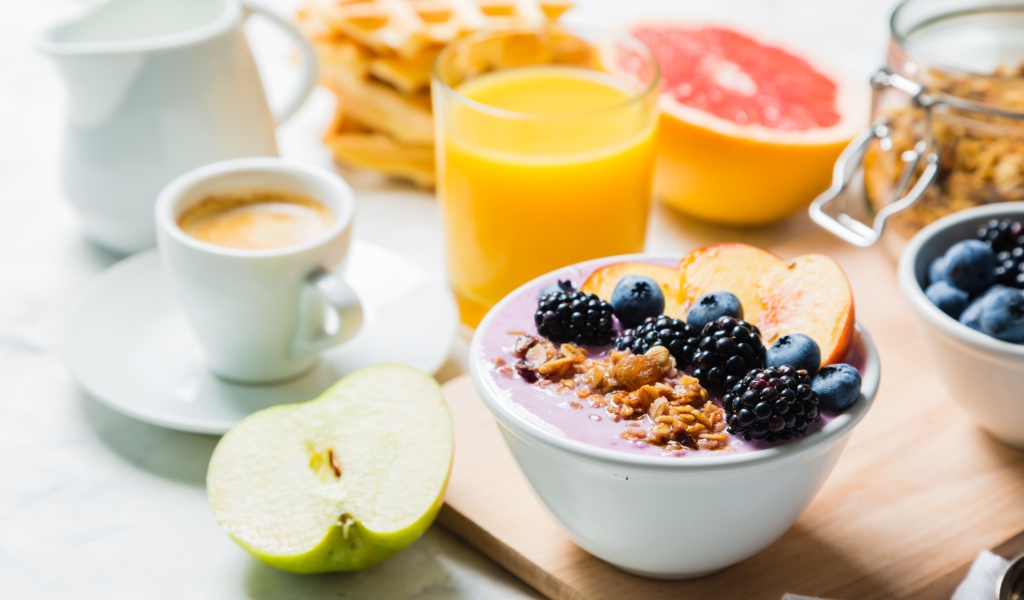 Завтрак с овсянкой, ягодами, фруктами и свежим соком на столе