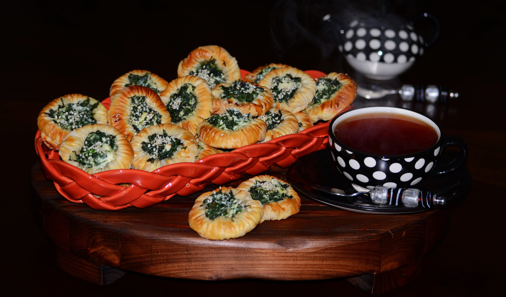 Булочки с зеленью и горячим чаем на черном фоне