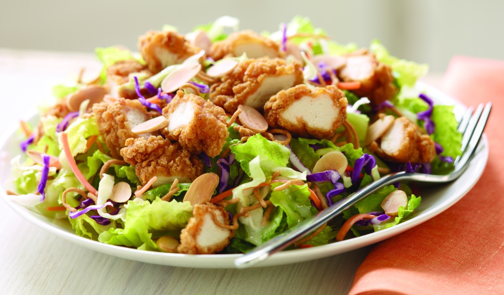 Куриный салат с орехами и капустой на тарелке