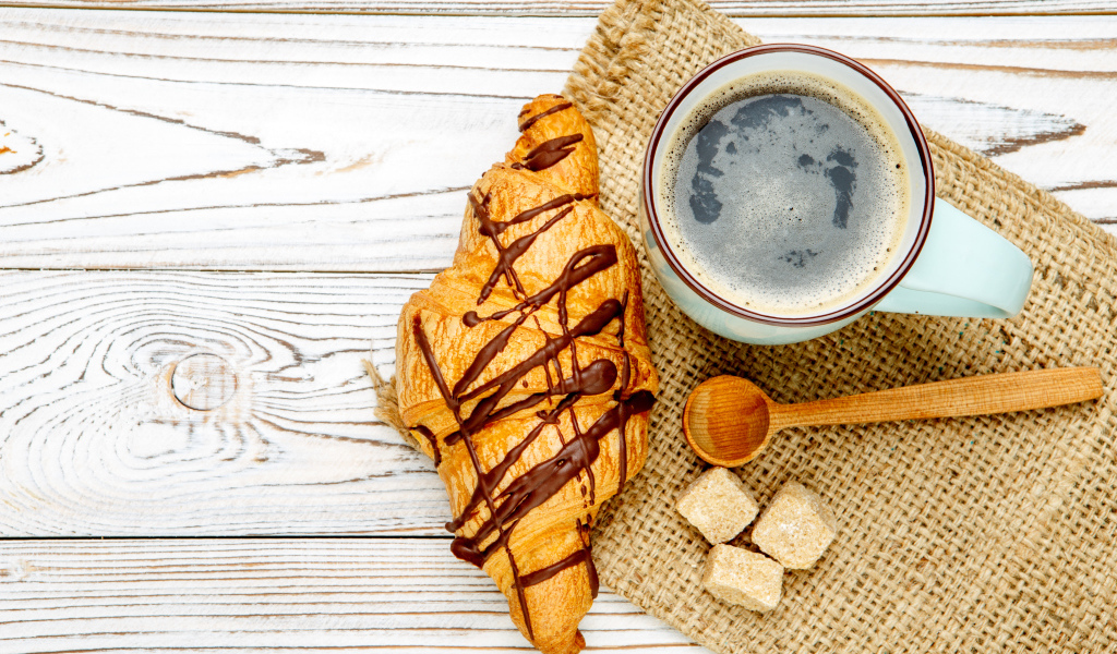 Круассан с шоколадом и чашкой кофе на столе