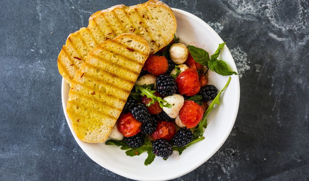 Гренки с салатом из ягод на белой тарелке