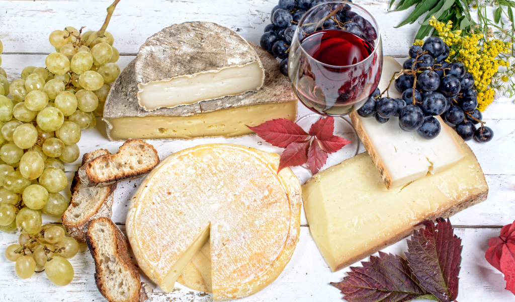 Дорогой сыр с плесенью на столе с виноградом и красным вином