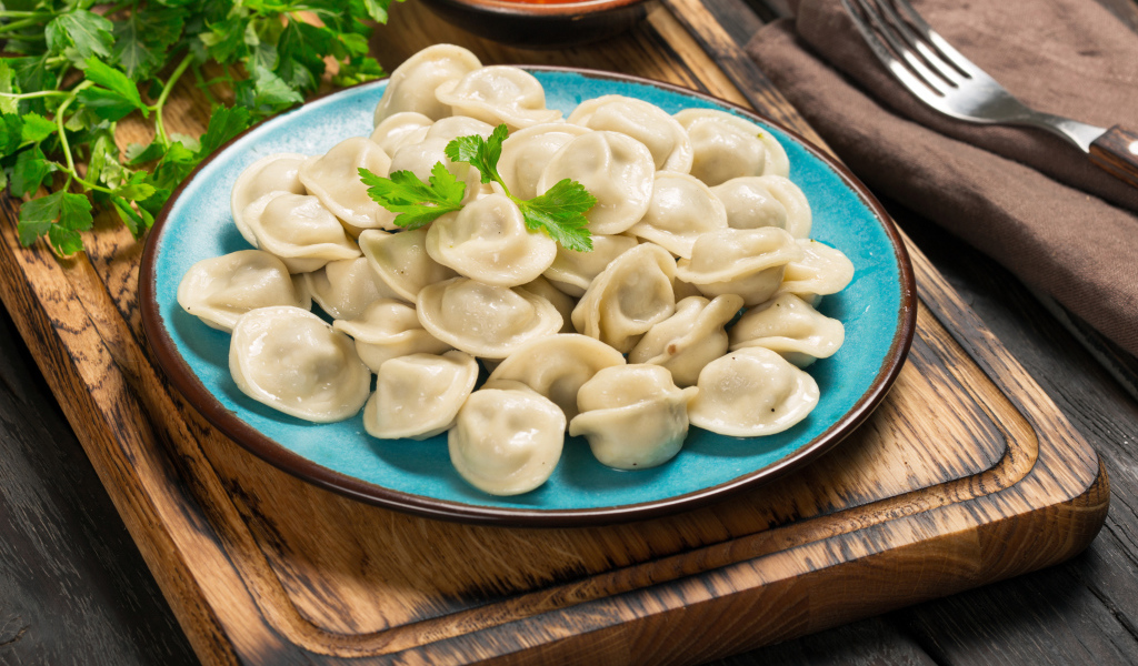 Вкусные пельмени на голубой тарелке 