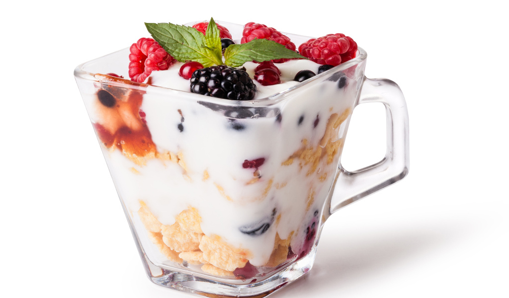 Хлопья с йогуртом и ягодами в стакане на белом фоне