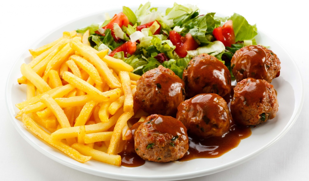 Картофель фри на белой тарелке с салатом и фрикадельками