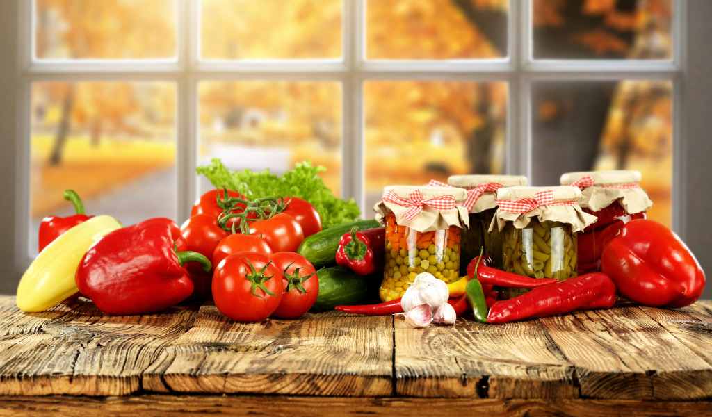 Свежие овощи и зимние заготовки на столе 