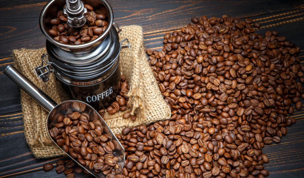 Жареные кофейные зерна с кофемолкой на столе