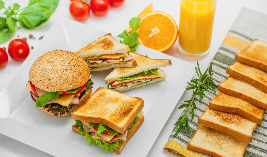 Гамбургер и сендвичи на столе с апельсиновым соком