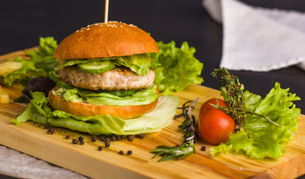 Гамбургер с зеленью на разделочной доске  