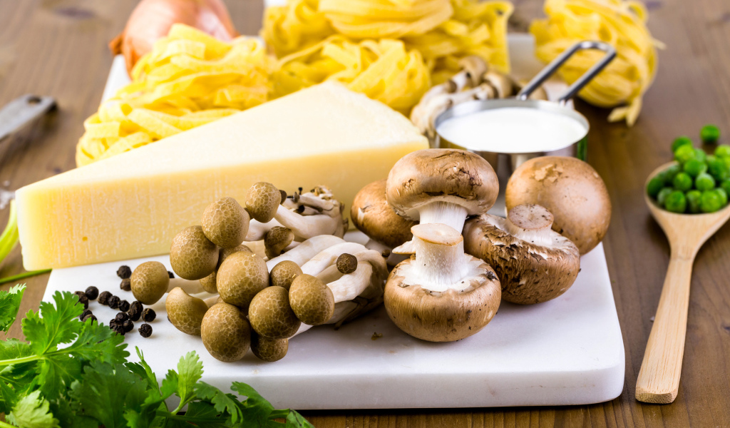 Грибы на разделочной доске с сыром, макаронами и зеленью