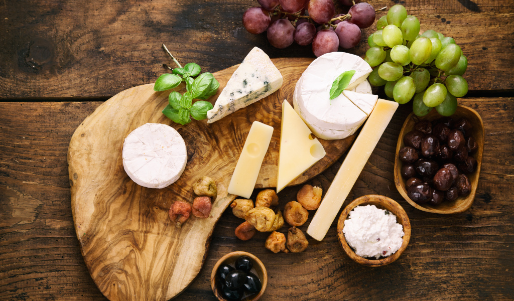 Кусочки сыра с виноградом и оливками на столе