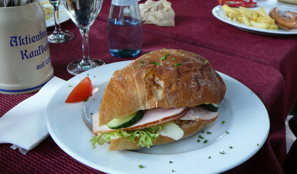 Сэндвич с ветчиной и овощами на столе в ресторане